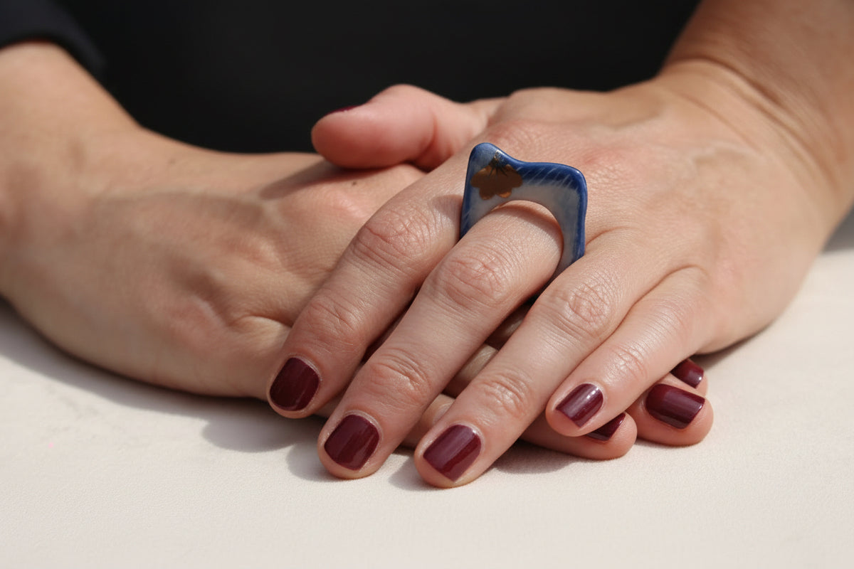 Bague carrée bleue aux éclats de feuille dorée.