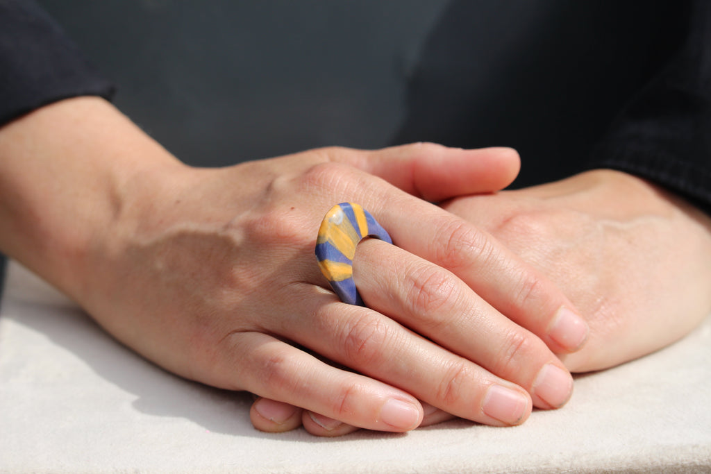 Bague en porcelaine bleue aux lignes orangées.