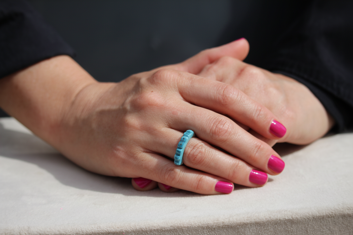Mains avec vernis rose vif et bague turquoise